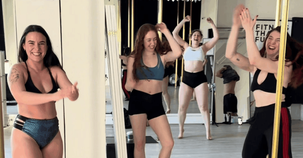 Students supporting each other through a beginner pole class at Achieve Pole Studio.